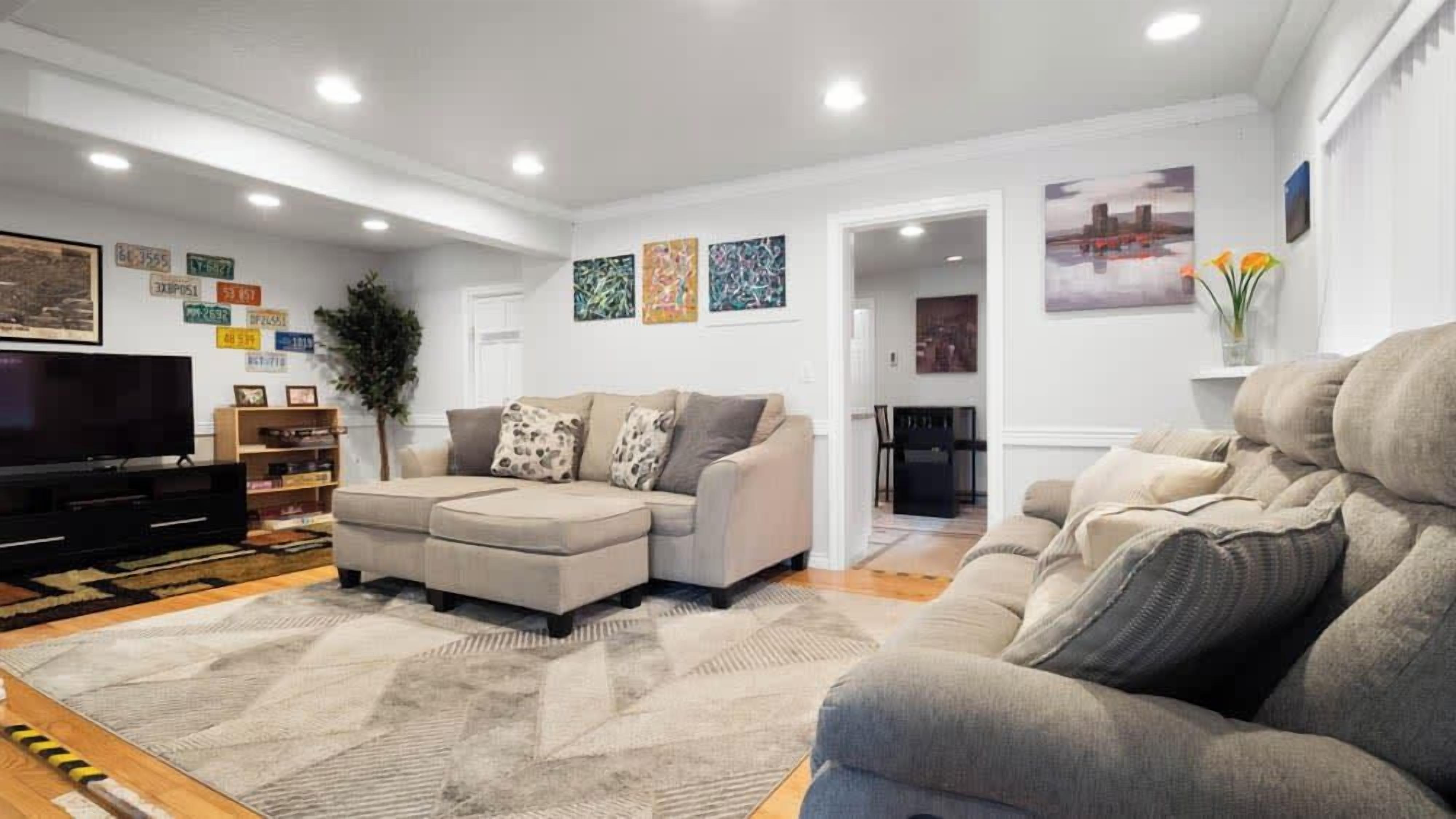 A modern living room with a sectional sofa, a flat-screen TV, and a large rug.