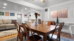 A dining area with a wooden table and chairs, a vase with flowers, and a window with striped blinds. - Sixth Street Victorian — Downtown Leadville (Leadville)