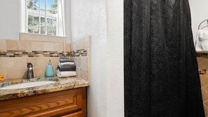 Une salle de bain avec un lavabo, un robinet, un porte-serviettes avec des serviettes pliées et une fenêtre au-dessus du lavabo.
