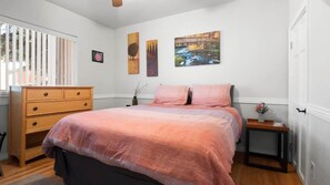 Une chambre à coucher avec un lit, une commode et des œuvres d’art accrochées au mur.