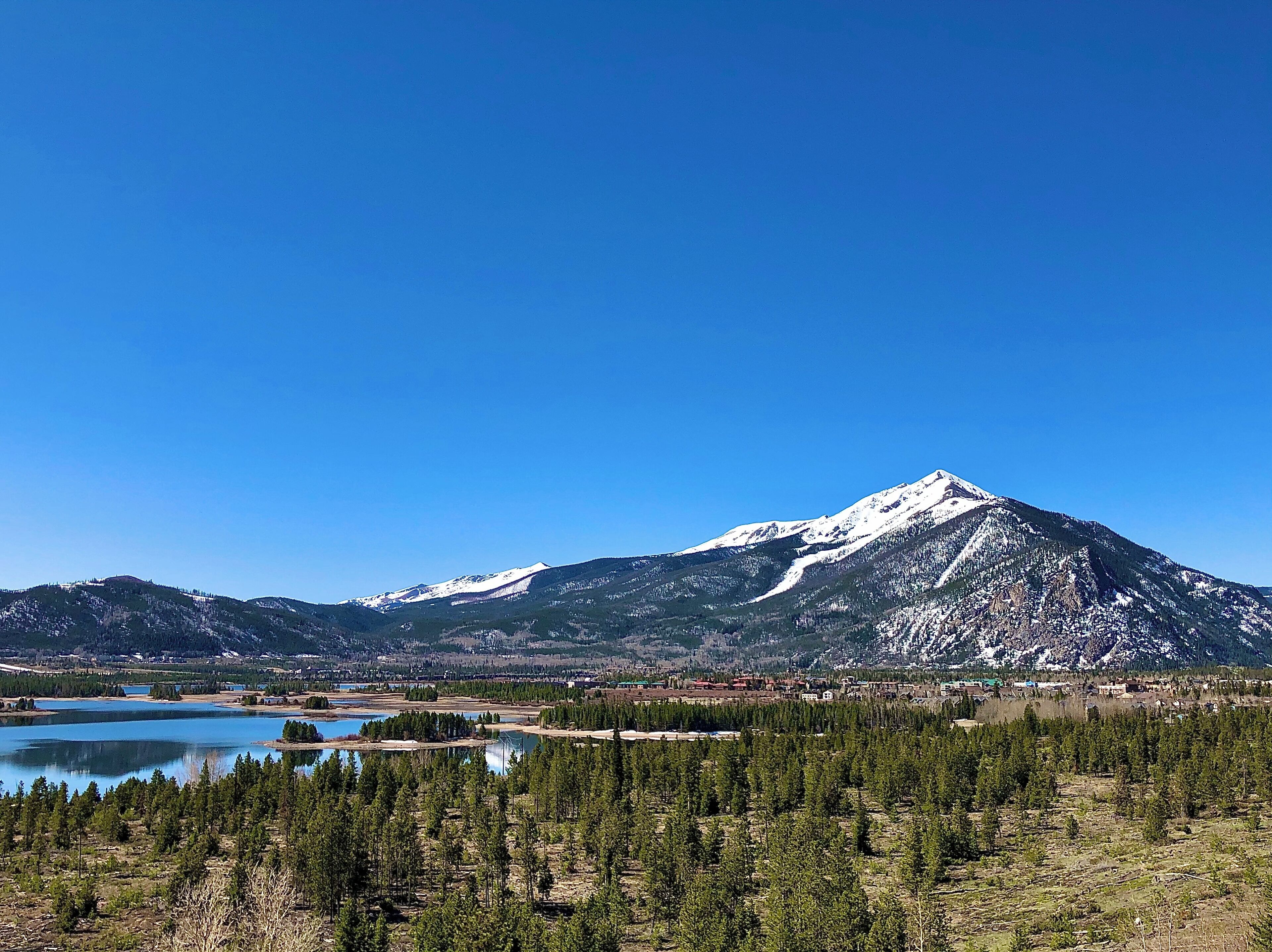 Une montagne avec un lac et une forêt au premier plan.