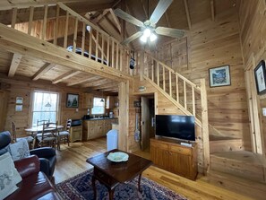 Uma cabana de madeira espaçosa com sala de jantar, cozinha e sala de estar.