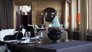 A dining table set with plates, cutlery, and glasses, with a decorative bowl and a chair in the background.