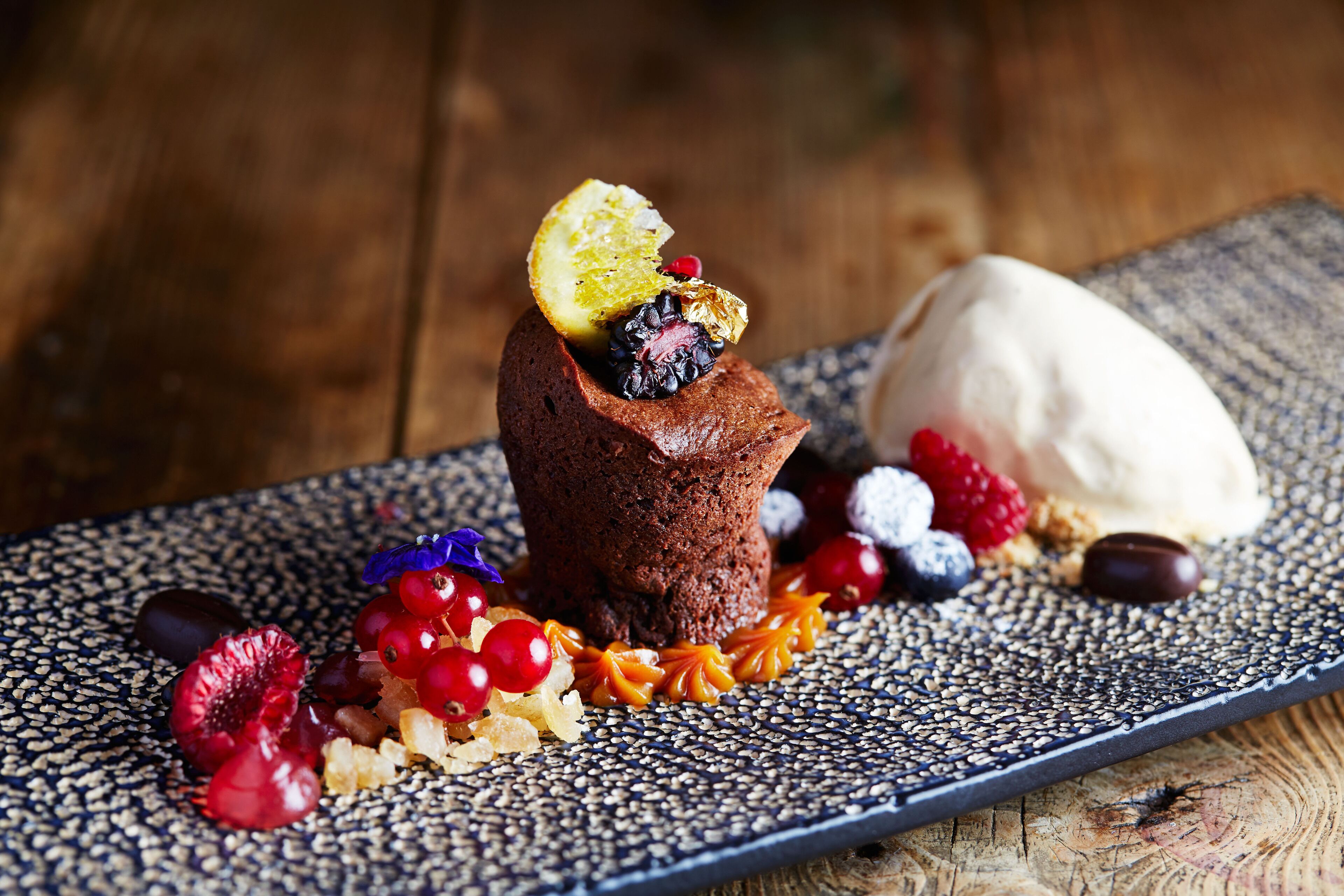 A dessert plate with a chocolate cake, berries, and a scoop of ice cream.