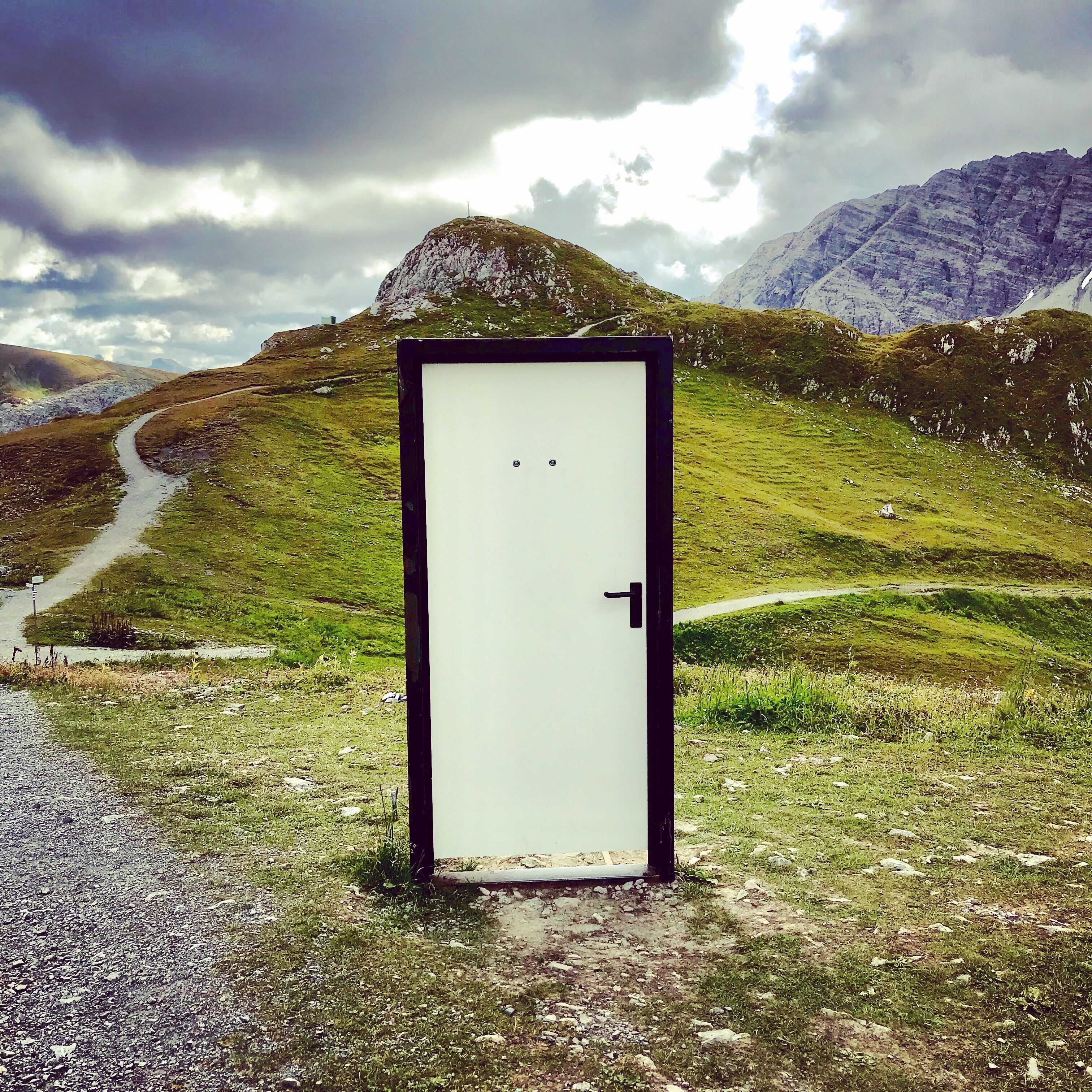 A door in a mountainous area with a path leading to it.