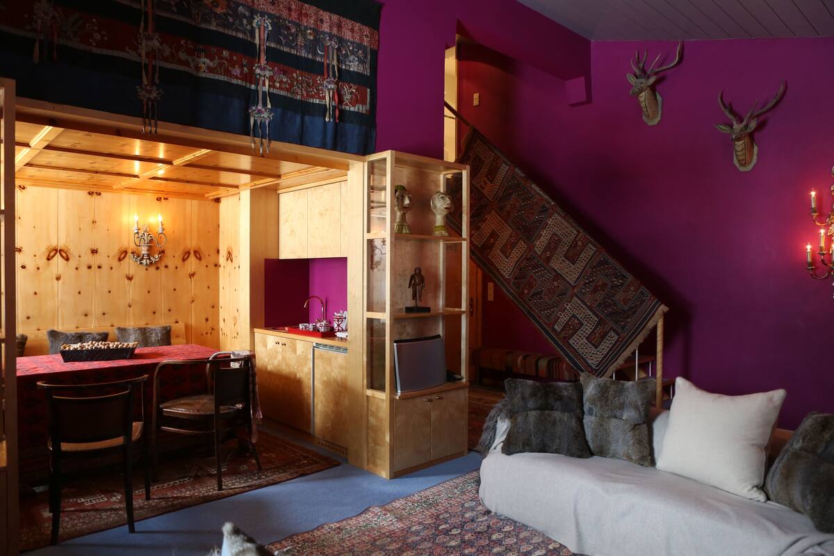 Une pièce chaleureuse avec un coin repas en bois, un canapé et un escalier.