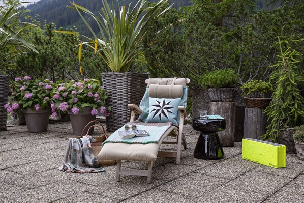 A patio area with a lounge chair, a small table, and various potted plants. - Kristiania Lech (Lech am Arlberg)