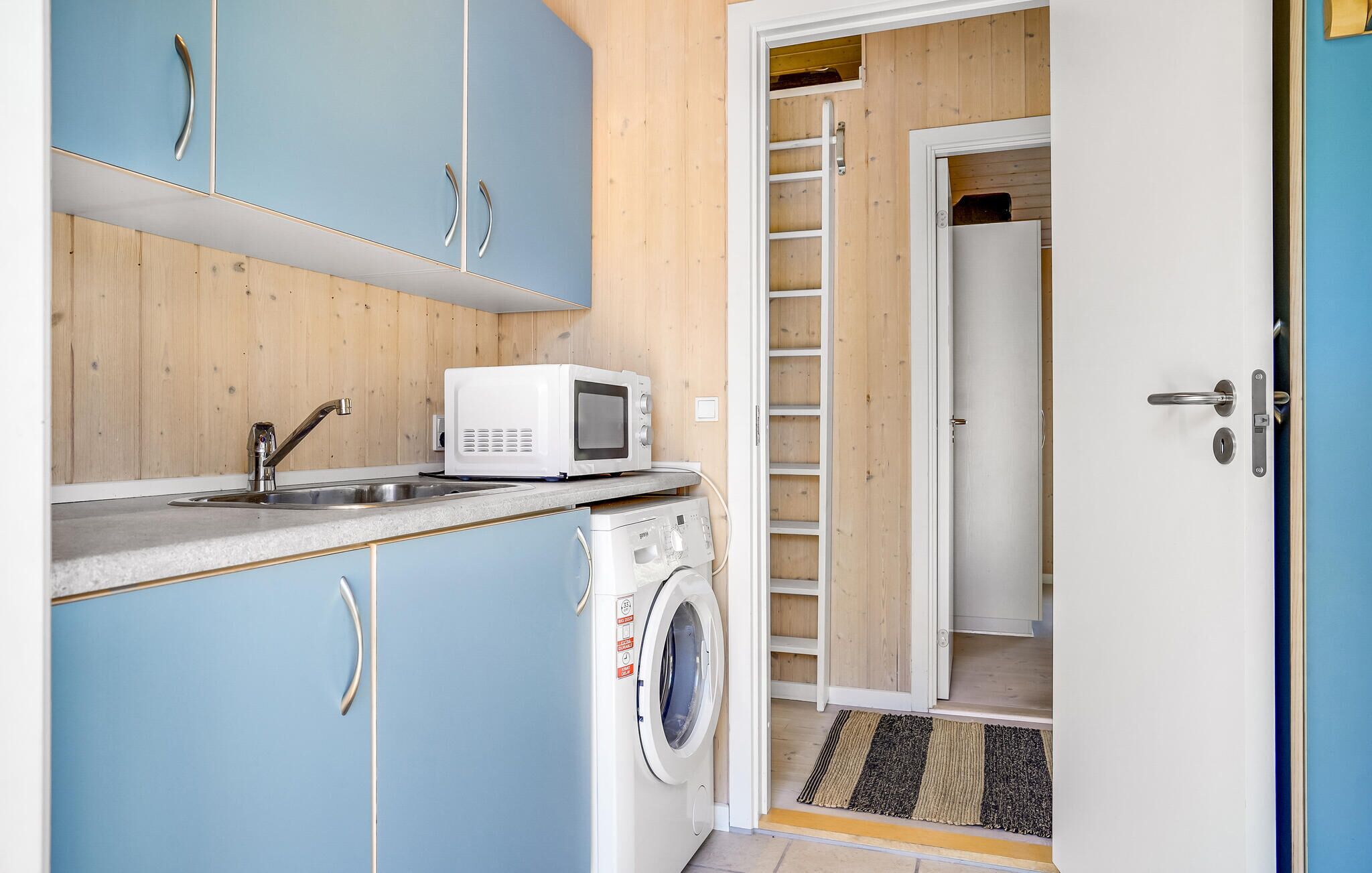 A compact kitchen with a washing machine, a microwave, and a sink.