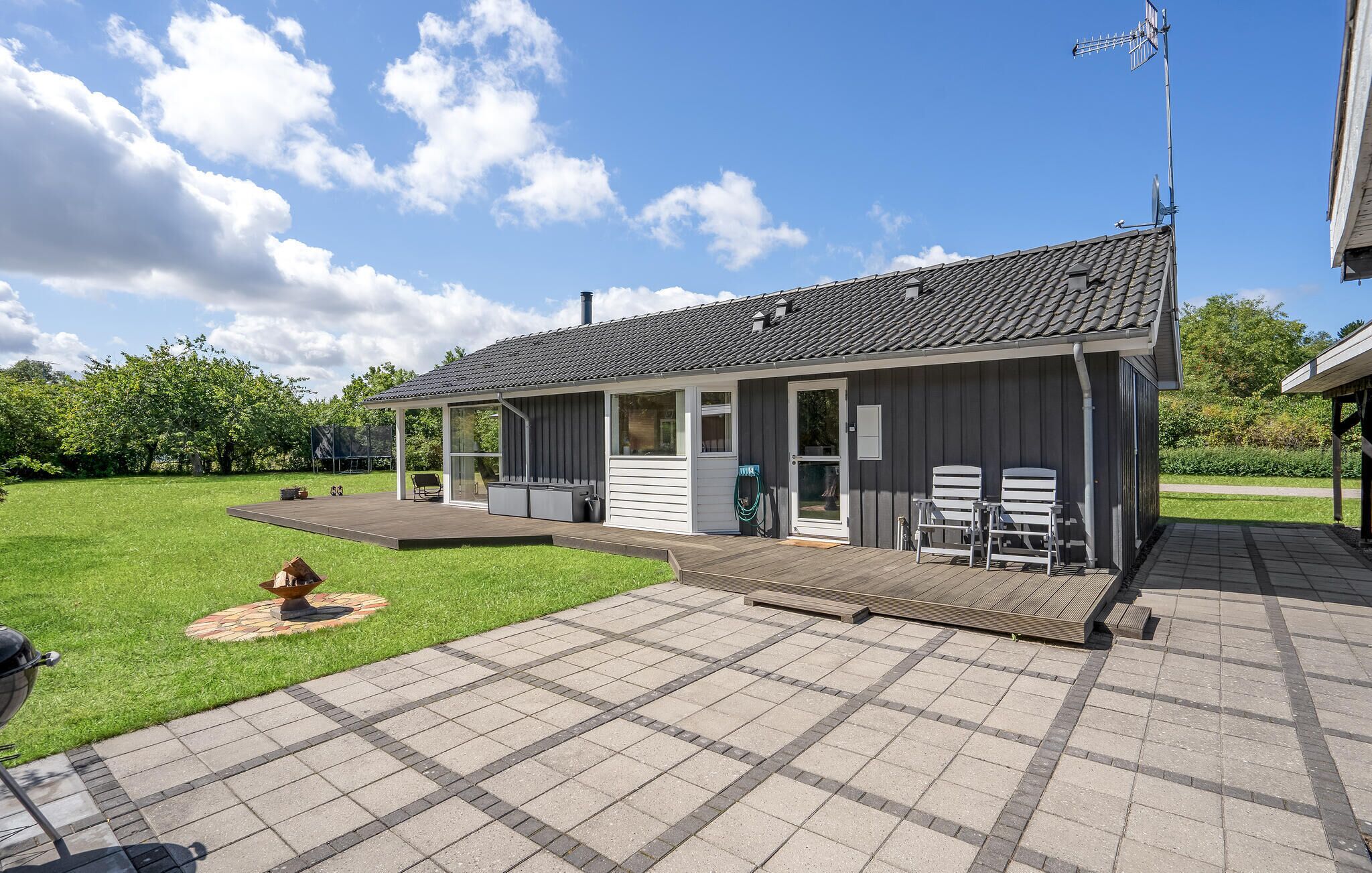 Una casa moderna con patio coperto, area barbecue e antenna parabolica.