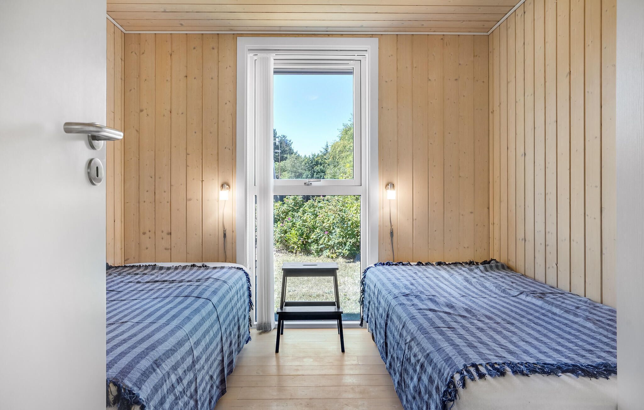 Una habitación pequeña con dos camas, una ventana y una puerta.