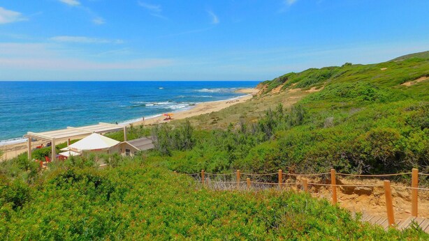 Une vue sur la côte, avec une plage, une construction dotée d’un toit blanc et une clôture.