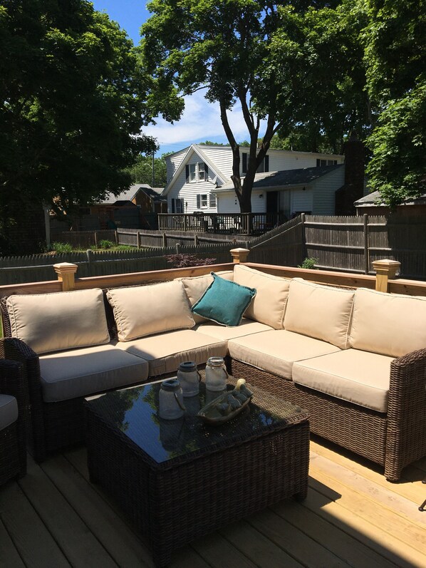 Relax in this outdoor seating area with a comfortable sofa and coffee table, surrounded by a deck with a view.