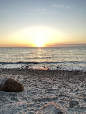 Enjoy a serene beach experience with a tranquil atmosphere and a natural rock formation.