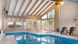 An indoor swimming pool with clear blue water, surrounded by white chairs and a wooden deck. - Bb103 Buffalo Ge 2br 2ba 2 Bedroom Condo by RedAwning (Silverthorne)