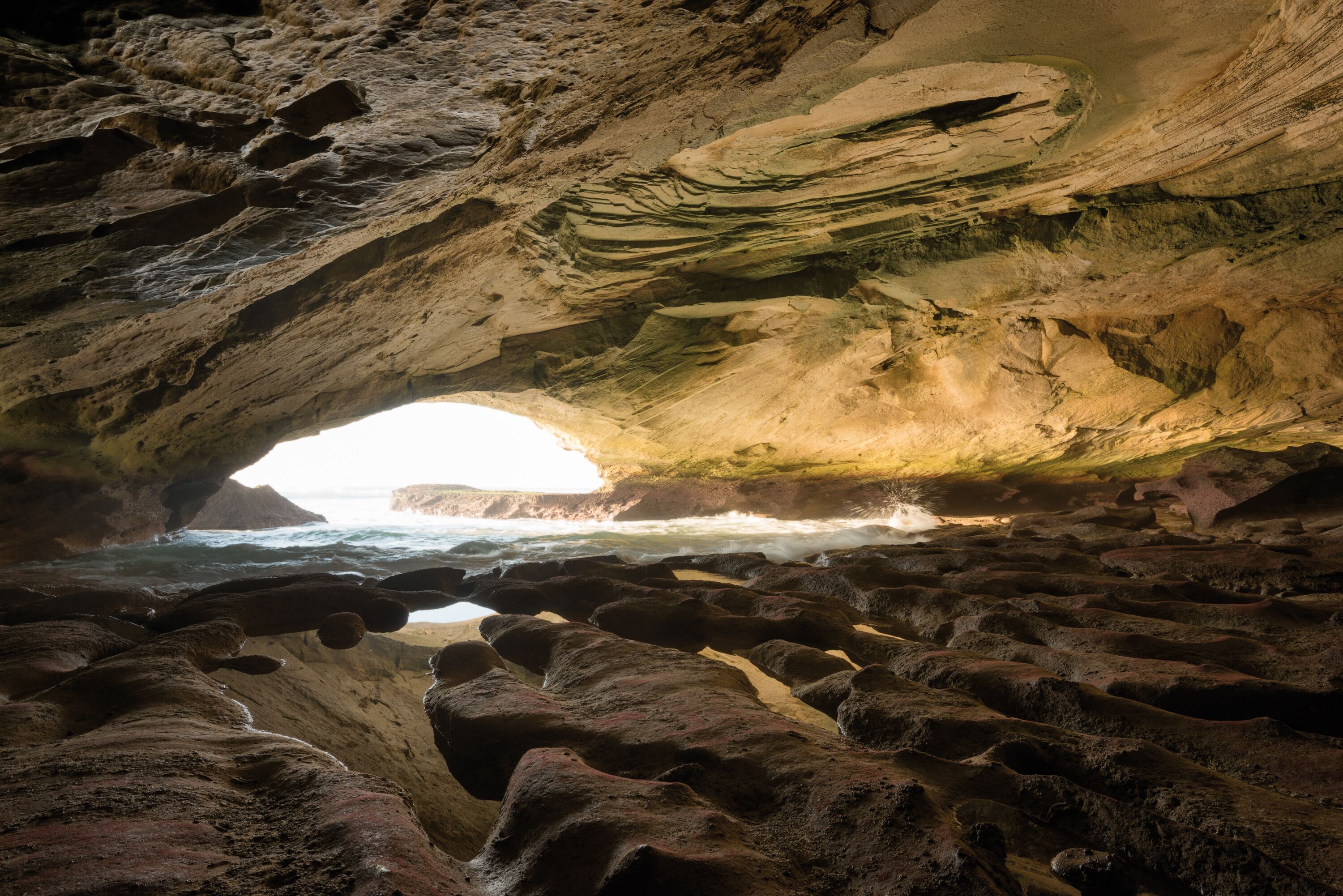 A cave with a natural archway leading to the ocean.