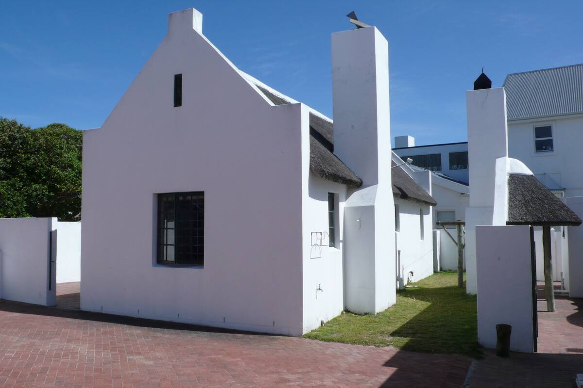 A white building with a sloped roof, a chimney, and a small window.