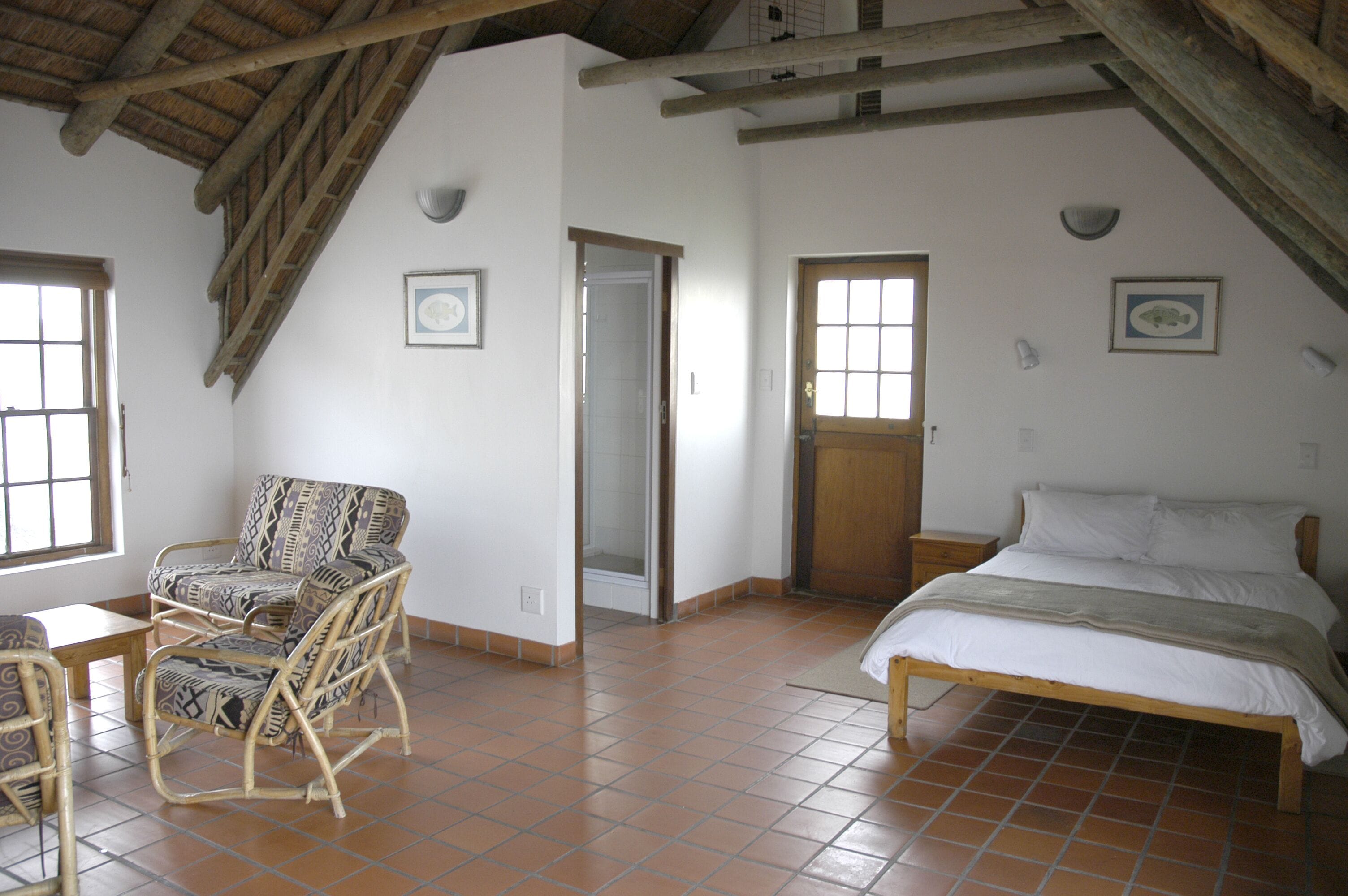 A room with a bed, a chair, a table, and a door.