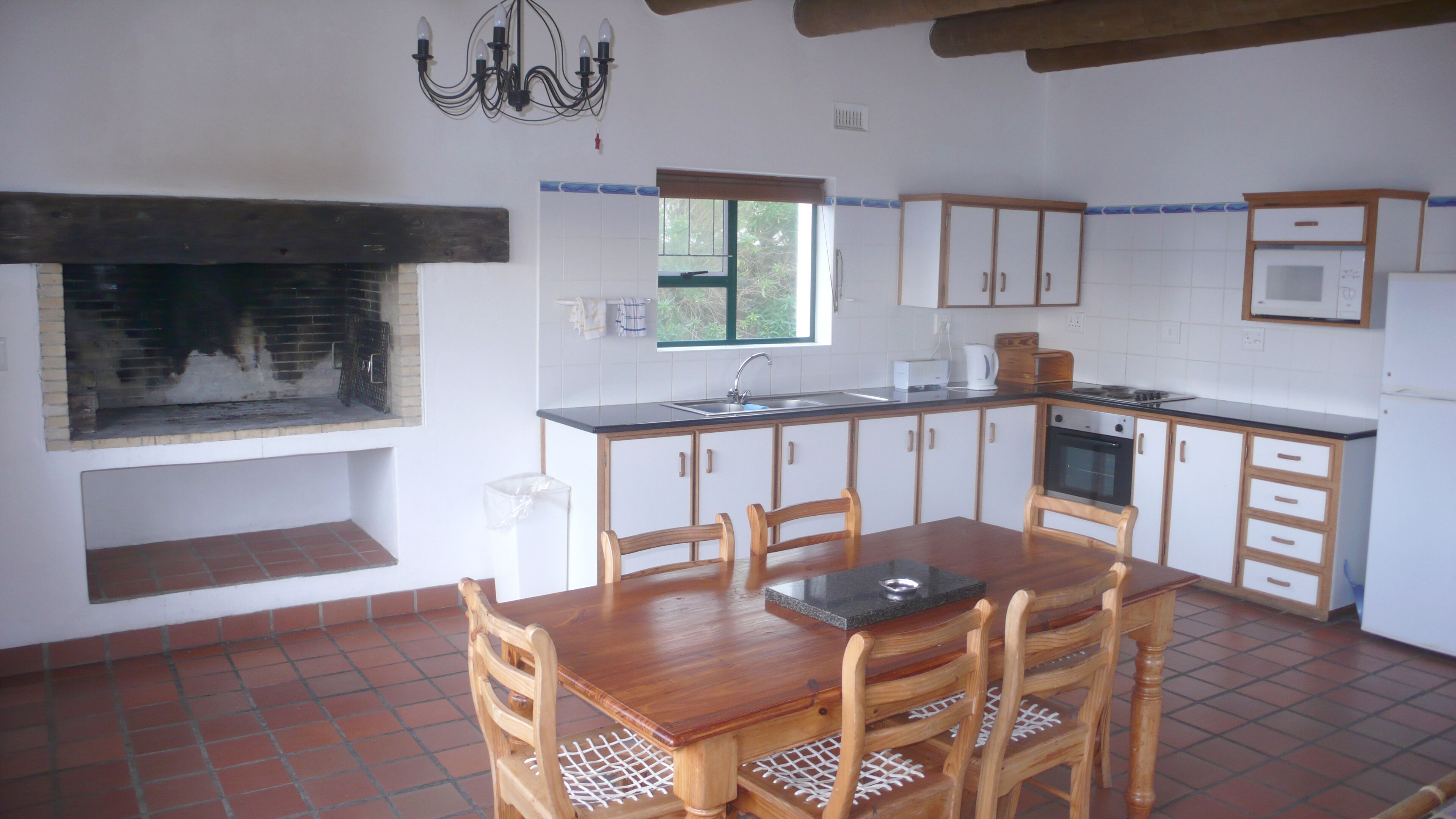 A kitchen with a dining table, chairs, a built-in oven, and a window.