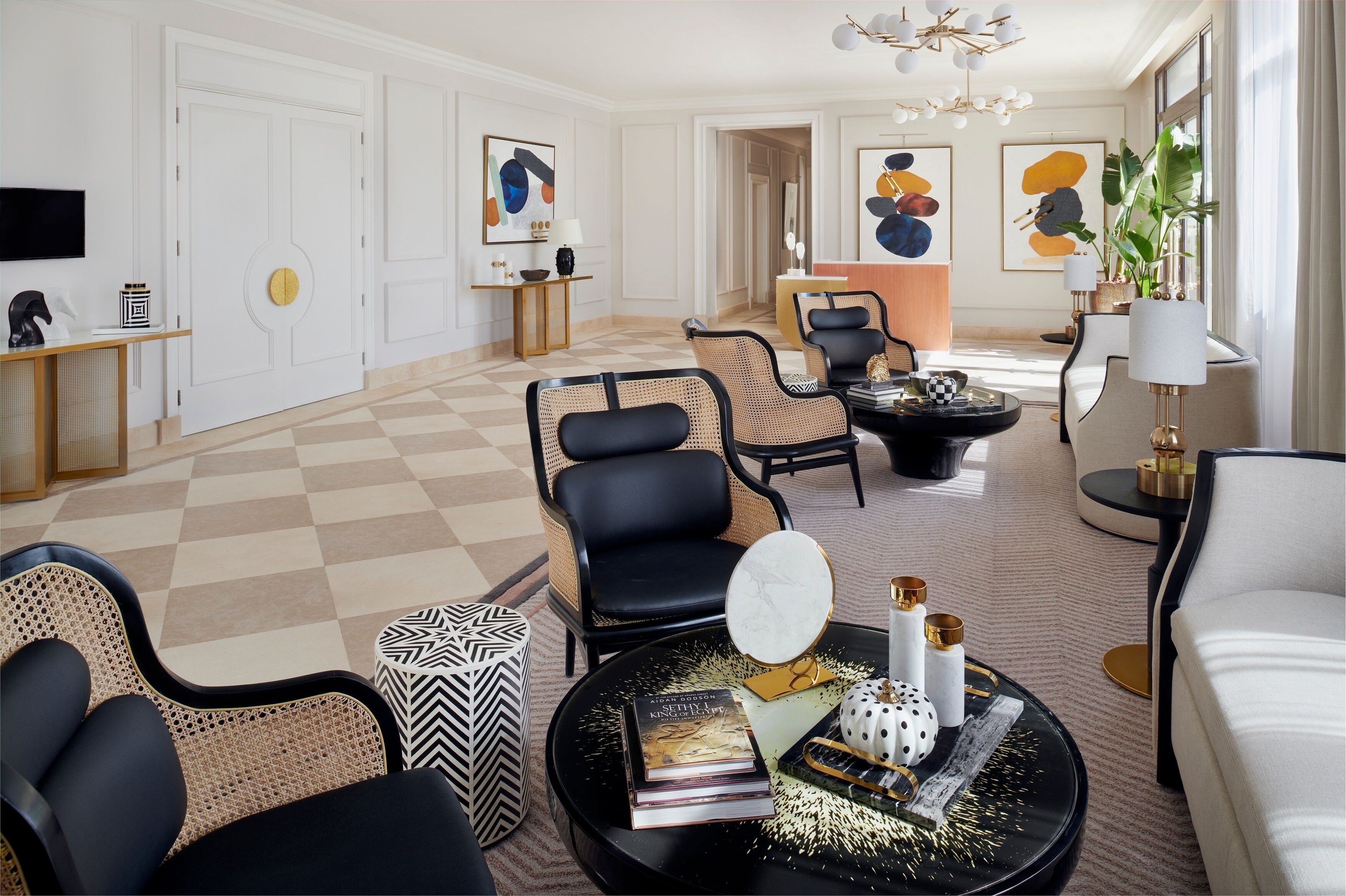 Ein geräumiges Wohnzimmer mit Schachbrettmuster-Boden, schwarzen und weißen Möbeln und einem Bücherregal.
