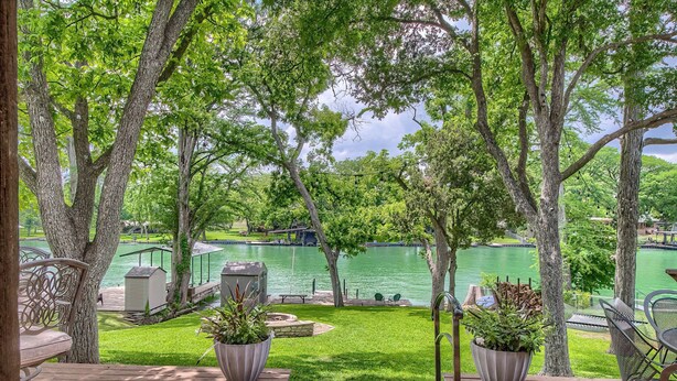 A deck with outdoor furniture, potted plants, and a view of a lake with boats. - Down River Haus Ld 727 3 Bedroom Home by RedAwning (New Braunfels)