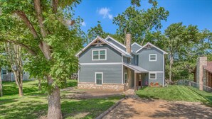 A two-story house with a stone foundation, a front porch, and a well-maintained lawn. - Down River Haus Ld 727 3 Bedroom Home by RedAwning (New Braunfels)