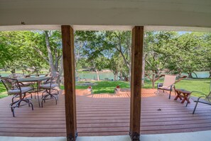 Una terraza de madera con mobiliario exterior, césped y un estanque.