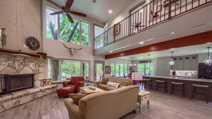 A spacious living area with a stone fireplace, a large sofa, and a high ceiling with a fan. - Down River Haus Ld 727 3 Bedroom Home by RedAwning (New Braunfels)