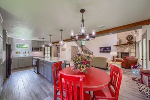 Una cocina amplia con una isla central, un comedor con sillas rojas y una sala de estar con chimenea.