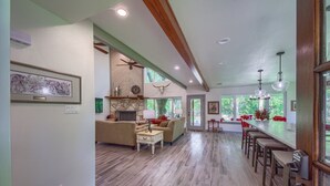 A spacious living area with a fireplace, sofas, and a dining area with bar stools. - Down River Haus Ld 727 3 Bedroom Home by RedAwning (New Braunfels)