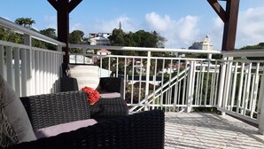 An outdoor seating area with wicker furniture and a white railing. - Cosy nest - Plage de Babin (Morne-À-l'Eau Guadeloupe)