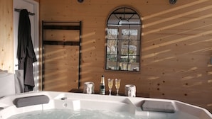 A wooden room with a hot tub, a clock, and a window with a view. - Gites du Moulin - Le Charmant (Lagardelle-sur-Lèze)