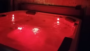 A hot tub with a red light, wooden walls, and three wall-mounted speakers. - Gites du Moulin - Le Charmant (Lagardelle-sur-Lèze)