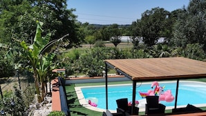 A wooden deck with a pool, surrounded by greenery and a clear sky. - Gites du Moulin - Le Charmant (Lagardelle-sur-Lèze)