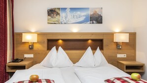 A double room with a wooden headboard, two bedside tables with lamps, and a wall-mounted phone. - Hotel Pongauerhof (Flachau)