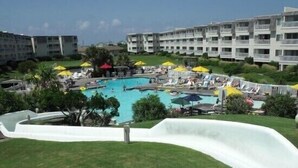 A swimming pool surrounded by lounge chairs and umbrellas, with a white slide leading into the pool. - Wide, Sandy Beaches Await You! (Atlantic Beach)