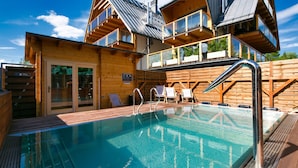 A wooden cabin with a swimming pool, outdoor seating, and a view of the surrounding forest. - Apartament with Hot Tub (Zakopane)