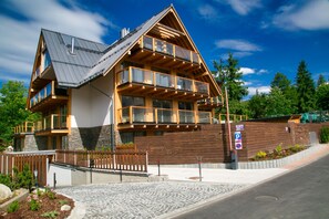A multi-story wooden house with balconies, a paved driveway, and a stone pathway leading to the entrance. - Apartament with Hot Tub (Zakopane)