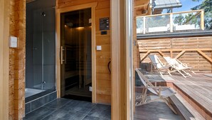 A wooden cabin with a glass-enclosed shower, a deck with lounge chairs, and a wooden deck railing. - Apartament with Hot Tub (Zakopane)