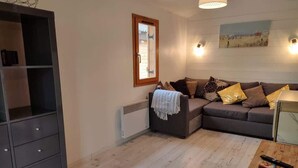 Un salon comprenant un canapé, une petite table, un meuble et un radiateur.