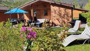 Une cabane en bois dotée d’un patio, de meubles d’extérieur et offrant une vue sur les montagnes.