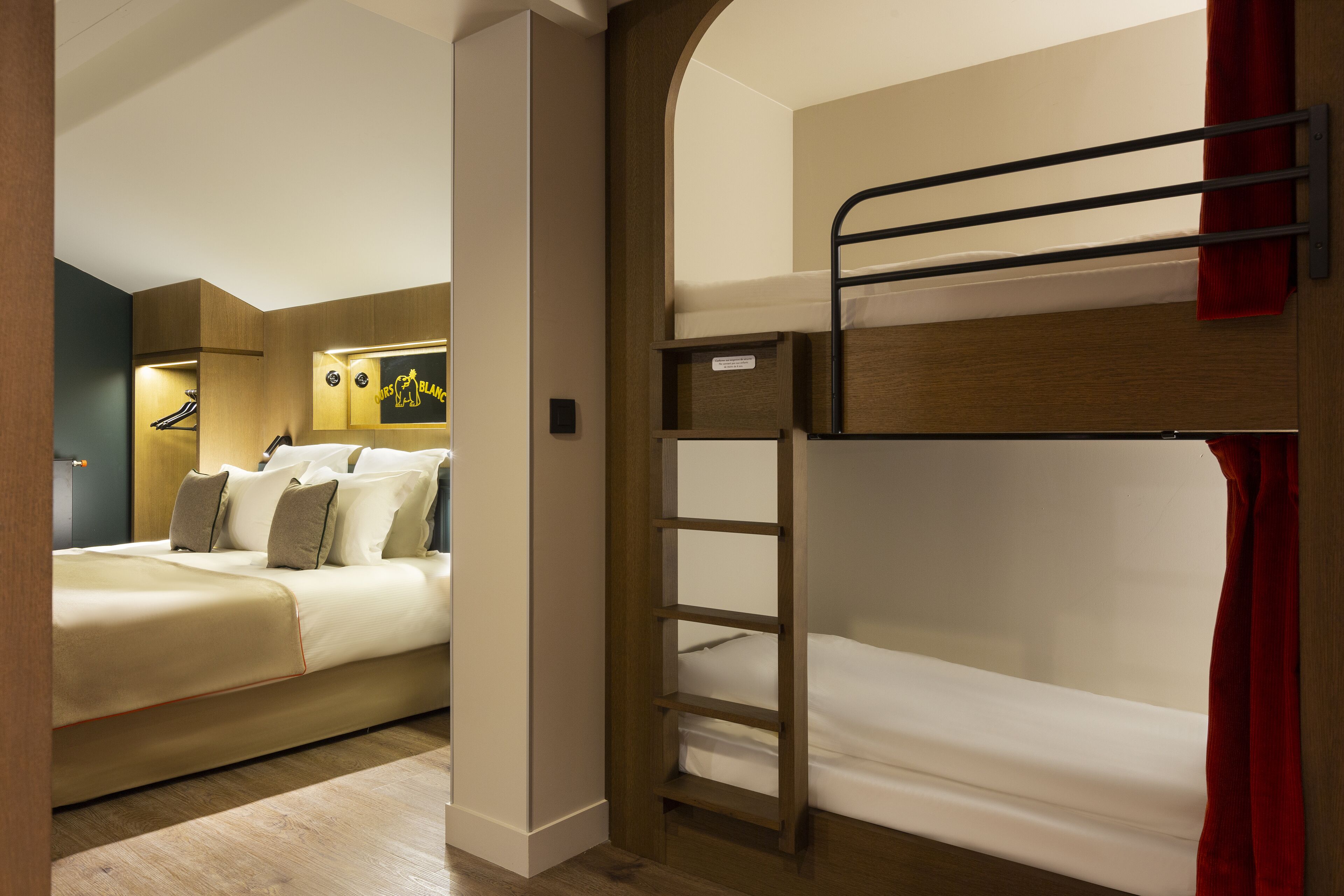 Una habitación de hotel con literas, un escritorio y un armario.