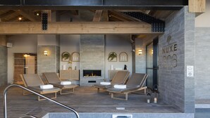 Un área de spa con piscina, sillas de descanso, chimenea y un cartel que dice "NUXE SPA".