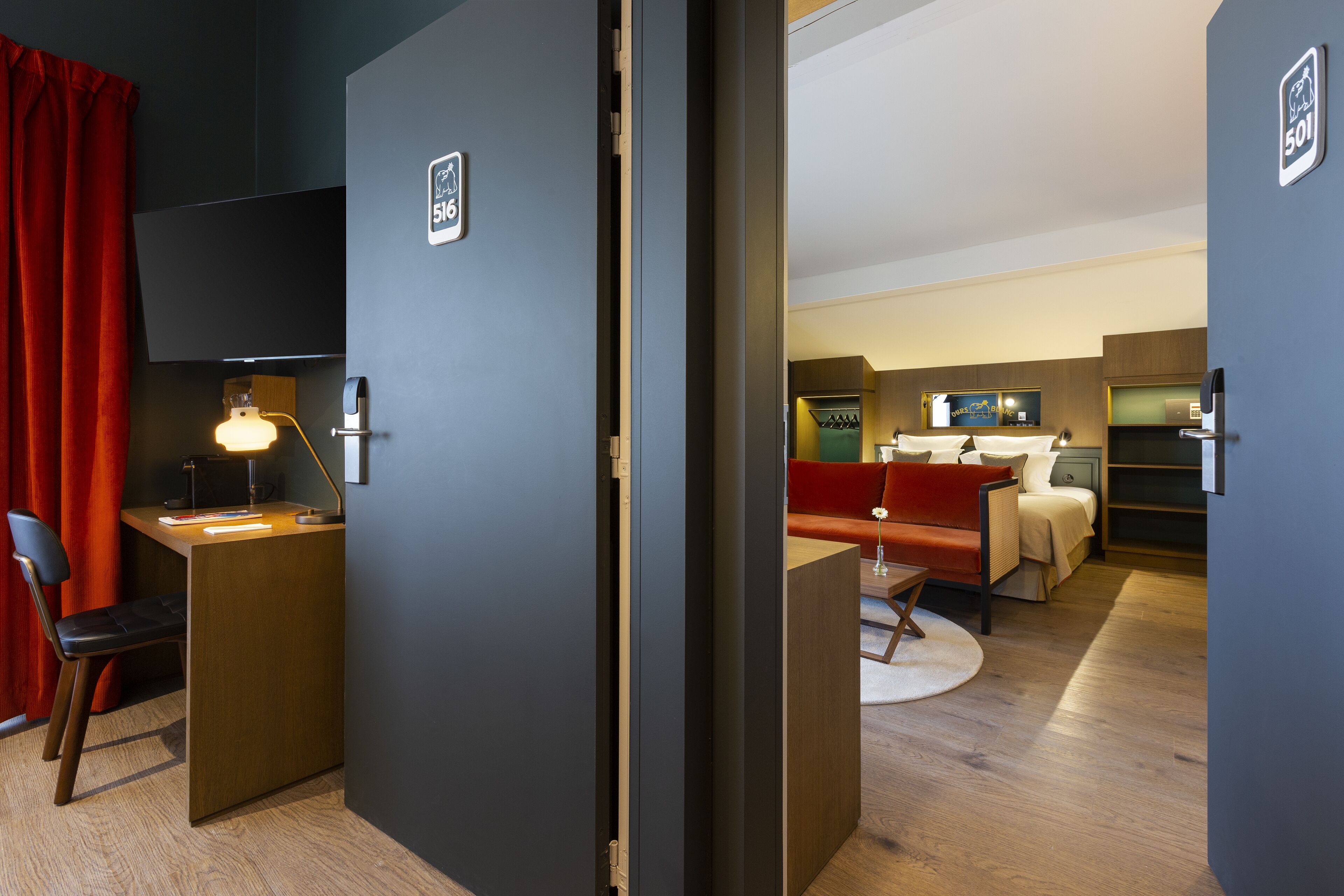 Una habitación de hotel con escritorio, silla y cama con cabecera roja.