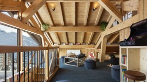Un interior de madera con vistas a montañas, estanterías y un tablero de ajedrez.