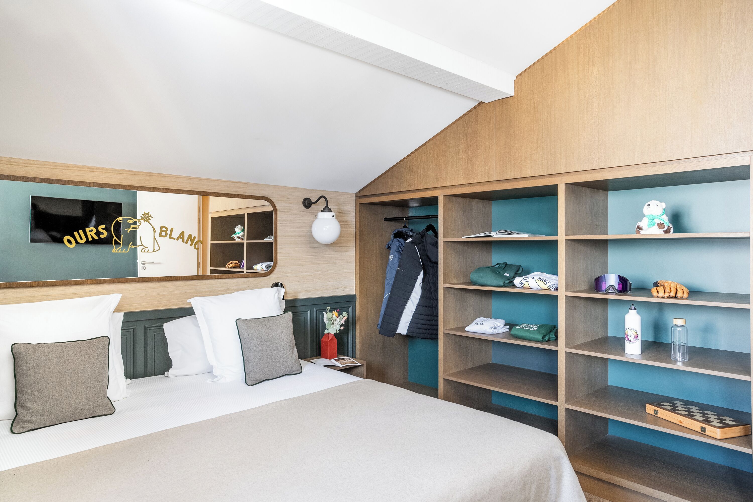 Ein Hotelzimmer mit Bett, Schrank, Spiegel und einem an der Wand befestigten Fernseher.