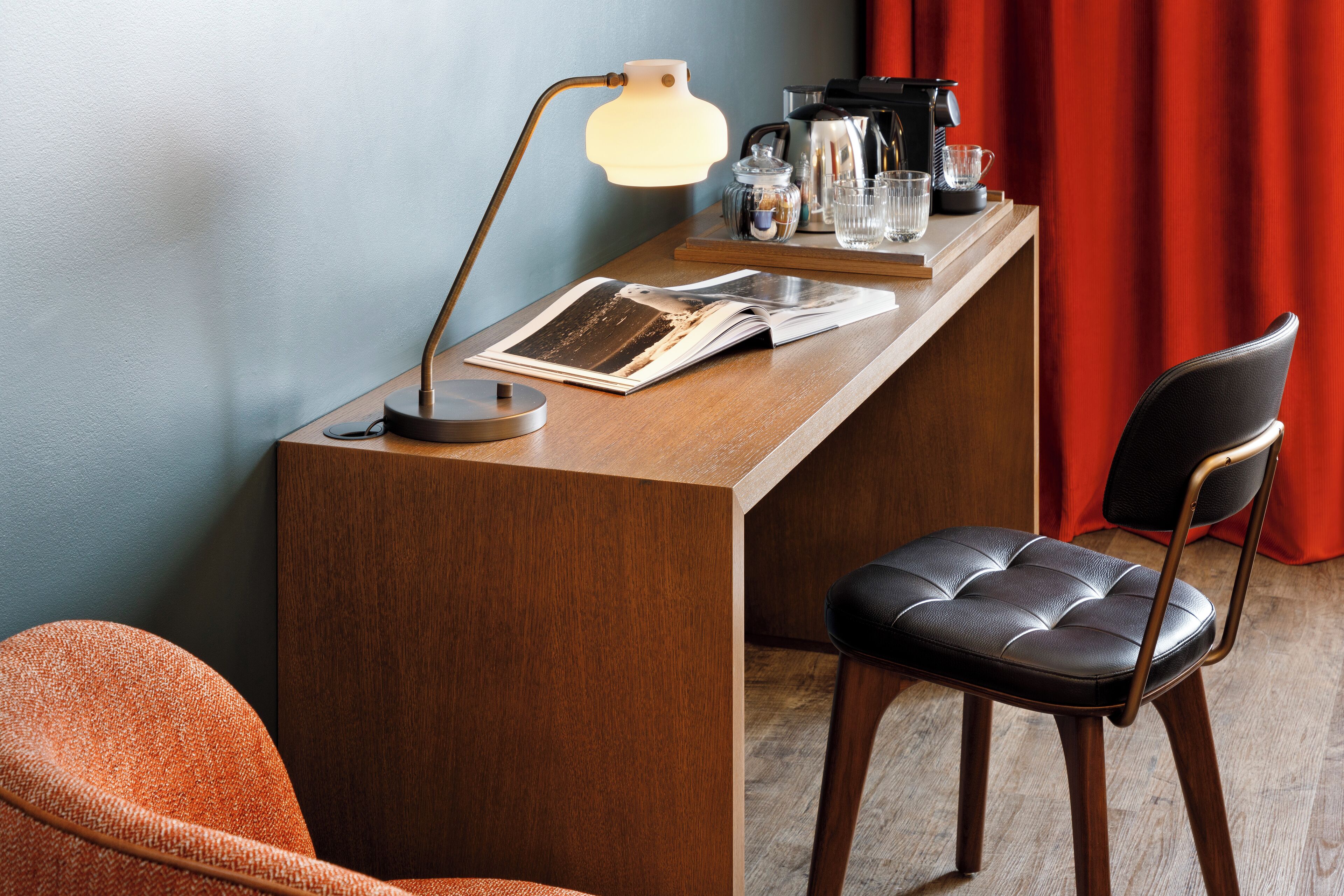 Un bureau en bois, une lampe, une chaise et une machine à café.