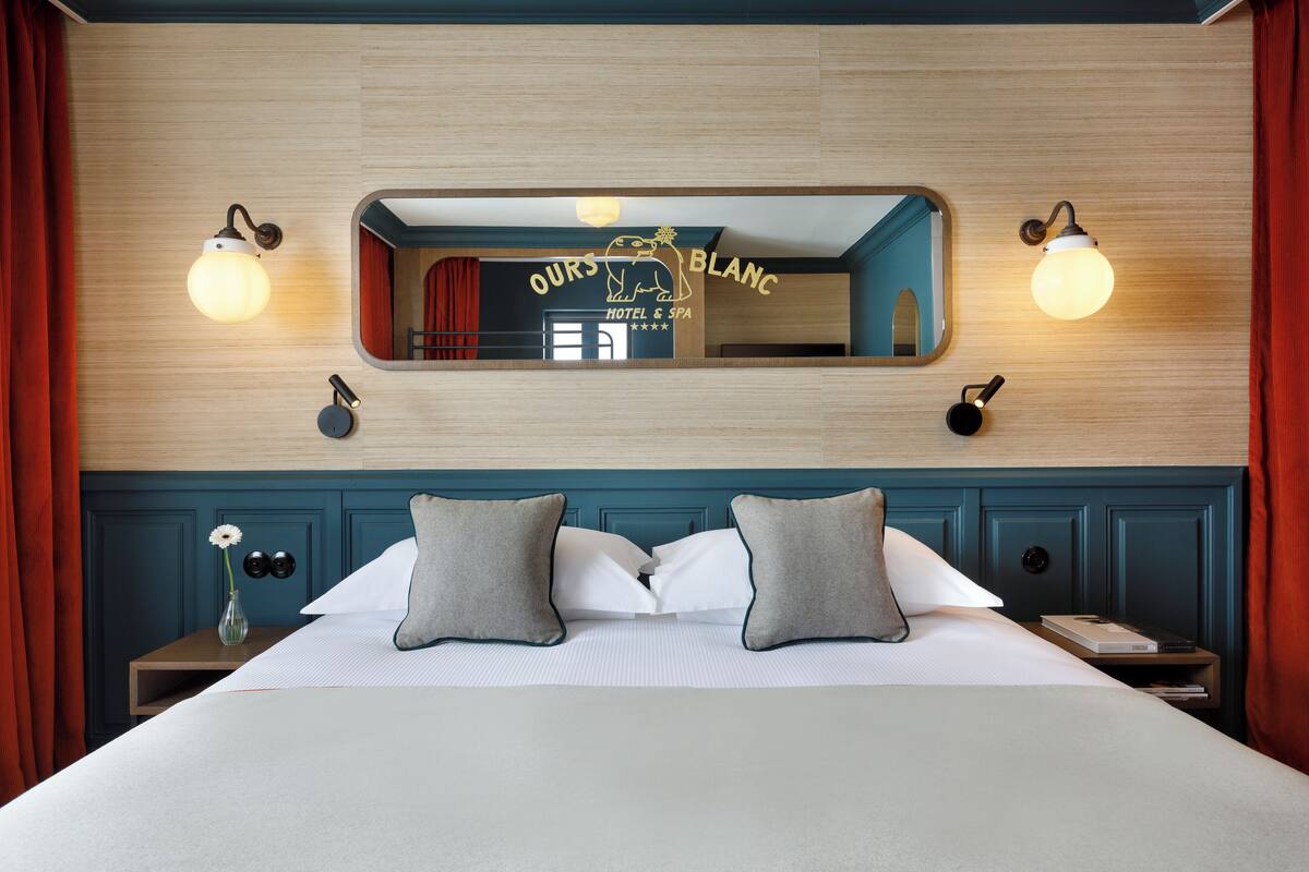 Ein Hotelzimmer mit Bett, zwei Nachttischen, einem Spiegel und Wandleuchten.