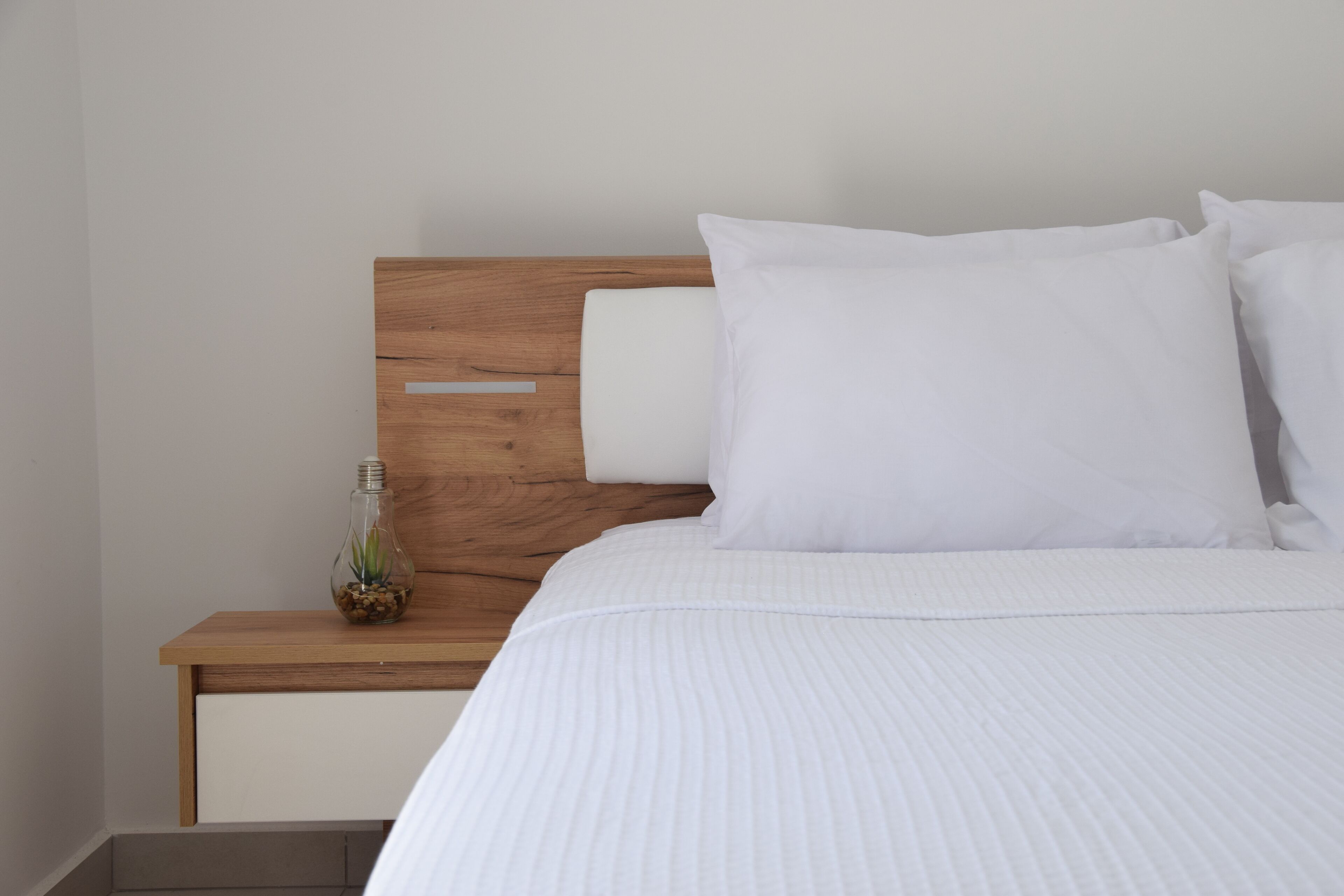 Una cama bien hecha con ropa de cama blanca y cabecera de madera.