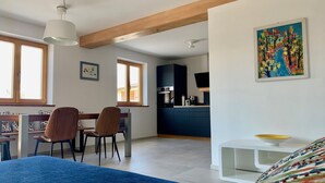 Ein modernes Schlafzimmer mit einem großen Bett, einem Schreibtisch mit Stühlen, einer Küchenzeile und einem Esstisch.