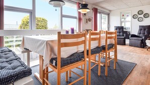 Ein Essbereich mit Holzkästen und einem Tisch, großen Fenstern und Blick auf Grünflächen.